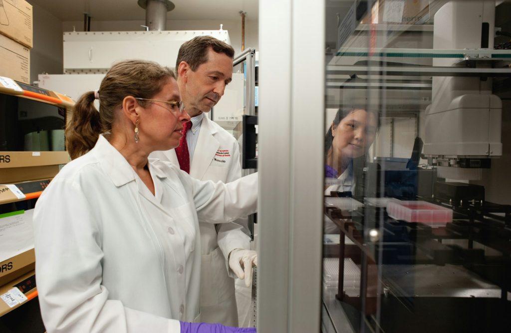 Scientists operating automated laboratory testing equipment