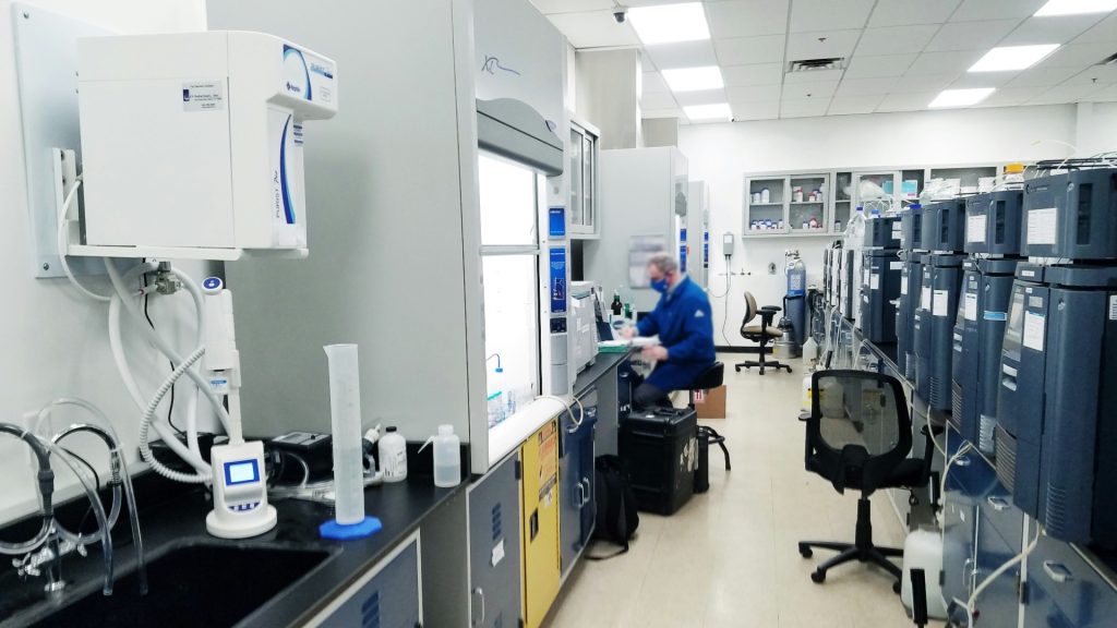 Scientist operating analytical equipment in a chemical compliance laboratory